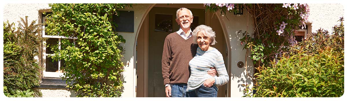 Older couple standing in the doorway of their home