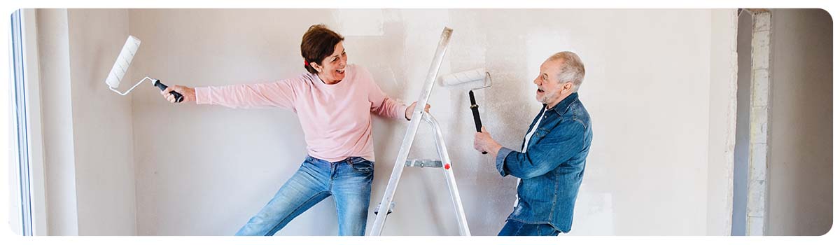A couple standing on a ladder with paint rollers