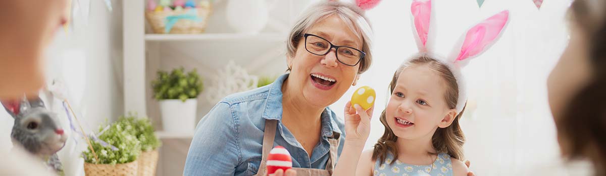 Grandmother and granddaughter painting Easter eggs