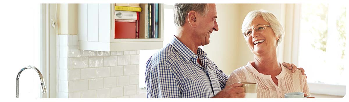 Happy retired couple drinking coffee in a bright kitchen